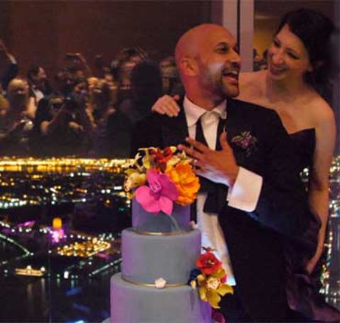 Keegan-Michael and Elisa Key standing beside their five-tier blue wedding cake.